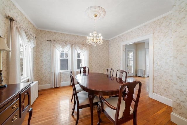 dining space featuring crown molding, radiator, light wood-style floors, baseboards, and wallpapered walls