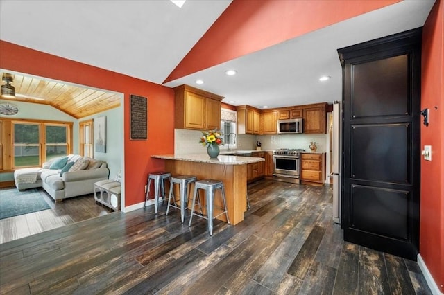 7 Scenic Dr, Wilbraham, MA 01095 - kitchen featuring appliances with stainless steel finishes, vaulted ceiling, a peninsula, dark wood-type flooring, and brown cabinets