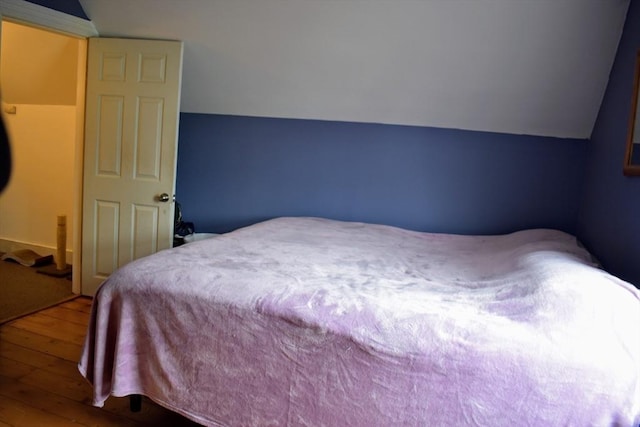 bedroom with hardwood / wood-style floors and lofted ceiling
