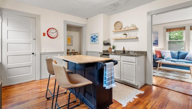 16 Desmond Ave, Manchester, MA 01944 - kitchen featuring wood counters, light wood-style floors, open shelves, a breakfast bar area, and a wainscoted wall