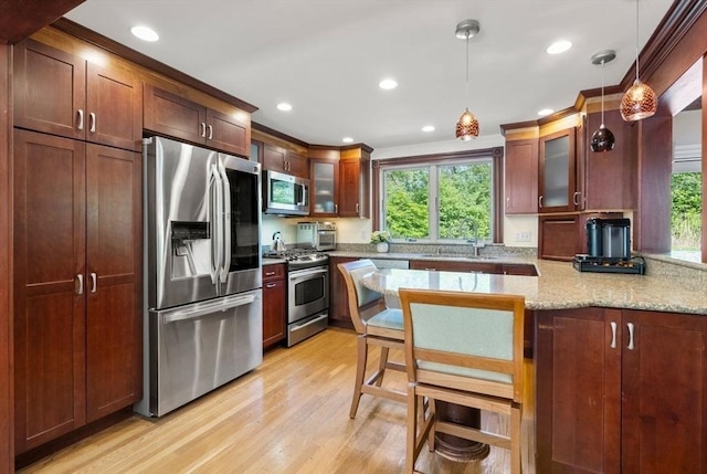 kitchen with stainless steel appliances, a sink, healthy amount of natural light, light wood finished floors, and recessed lighting
