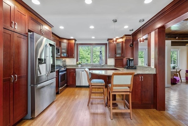 kitchen with appliances with stainless steel finishes, plenty of natural light, glass insert cabinets, a peninsula, and crown molding