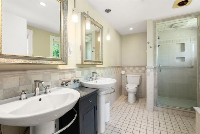 full bathroom with a shower stall, tile walls, tile patterned flooring, toilet, and a wainscoted wall