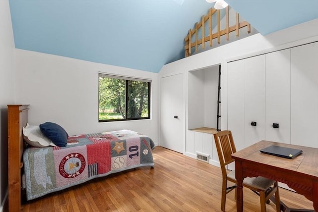 bedroom with wood finished floors and lofted ceiling