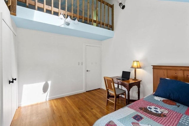 bedroom featuring wood finished floors, baseboards, and a towering ceiling
