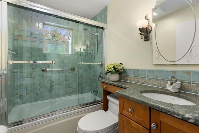 bathroom featuring toilet, vanity, enclosed tub / shower combo, and tasteful backsplash