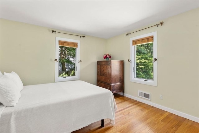 bedroom featuring light wood-style floors, multiple windows, and baseboards