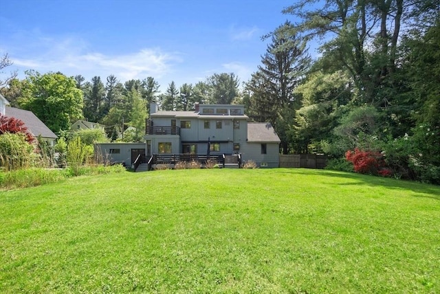 rear view of house featuring a balcony, a chimney, and view of scattered trees