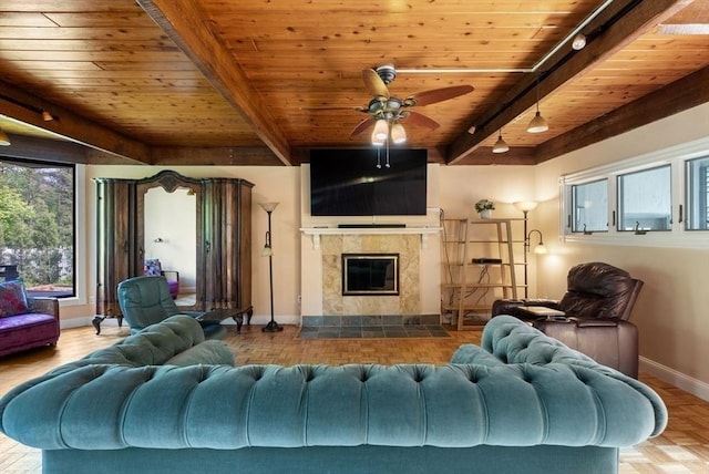 living room featuring baseboards, wood ceiling, beamed ceiling, ceiling fan, and a tiled fireplace