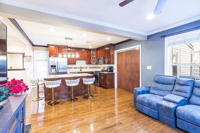 kitchen with pendant lighting, appliances with stainless steel finishes, a kitchen breakfast bar, a kitchen island, and light wood-type flooring