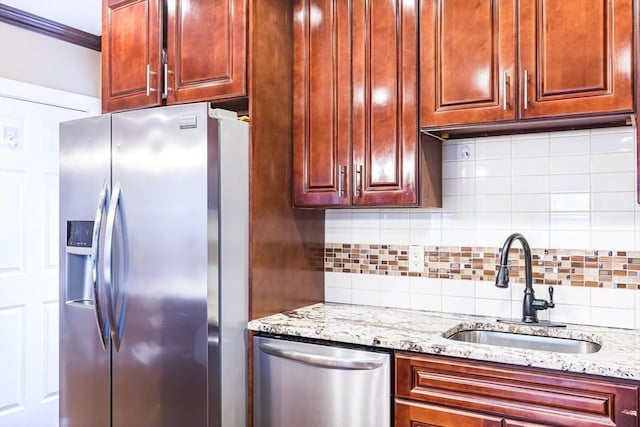 kitchen featuring sink, light stone counters, crown molding, tasteful backsplash, and appliances with stainless steel finishes