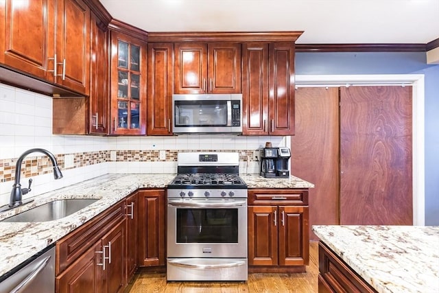 kitchen featuring light stone counters, sink, decorative backsplash, and appliances with stainless steel finishes