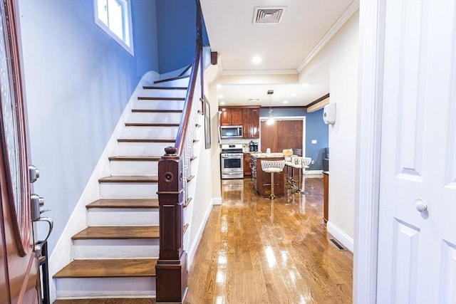 stairway with hardwood / wood-style floors and crown molding