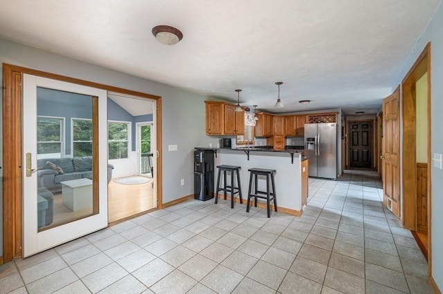 10 Tobin Dr, Dudley, MA 01571 - kitchen featuring stainless steel fridge, a peninsula, brown cabinets, a breakfast bar, and light tile patterned floors