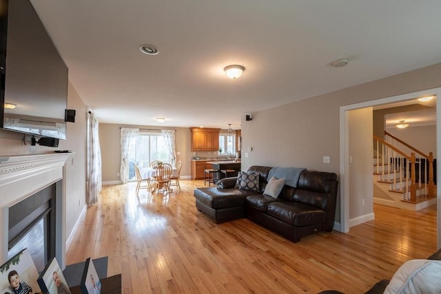 225 Salem Rd, Dracut, MA 01826 - living area featuring a glass covered fireplace, stairway, light wood finished floors, and baseboards