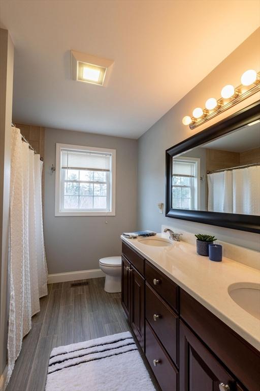 225 Salem Rd, Dracut, MA 01826 - bathroom featuring double vanity, toilet, wood finished floors, and baseboards