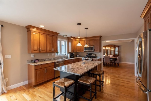 225 Salem Rd, Dracut, MA 01826 - kitchen with stainless steel appliances, brown cabinetry, a sink, light wood-type flooring, and light stone counters