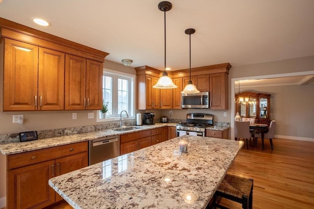 225 Salem Rd, Dracut, MA 01826 - kitchen with appliances with stainless steel finishes, a sink, brown cabinets, a kitchen island, and a breakfast bar