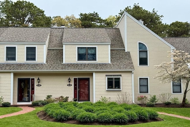 view of front of house with a shingled roof and a front yard