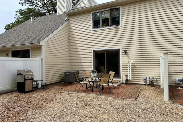 back of house with a chimney, a patio area, central air condition unit, a shingled roof, and fence