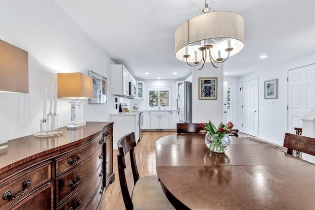 dining area with light wood finished floors, recessed lighting, and a chandelier