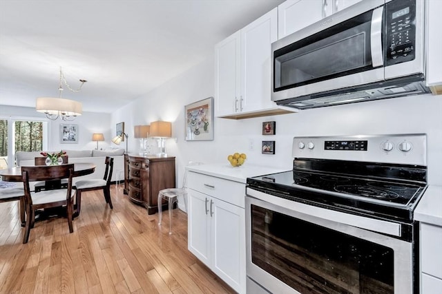 kitchen featuring stainless steel appliances, a chandelier, white cabinetry, and light countertops