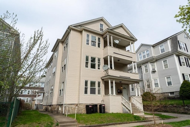 view of front facade with fence, a front lawn, and a balcony