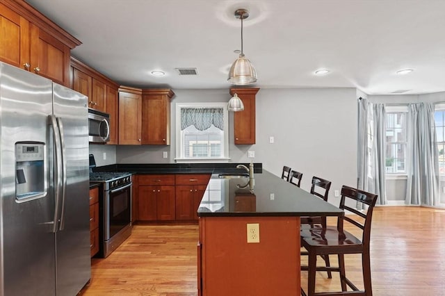 90 Litchfield Unit A, Boston, MA 02135 - kitchen featuring stainless steel appliances, a breakfast bar area, dark countertops, light wood-style floors, and recessed lighting