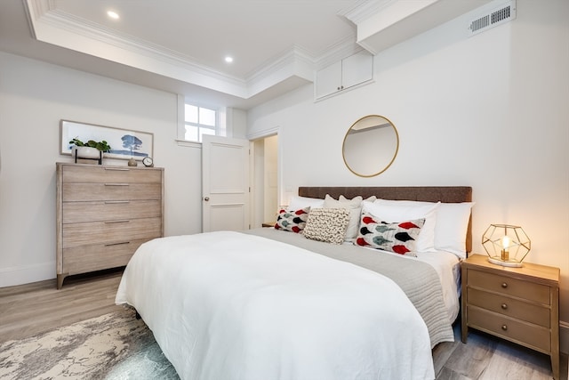 bedroom with a raised ceiling and light wood-type flooring