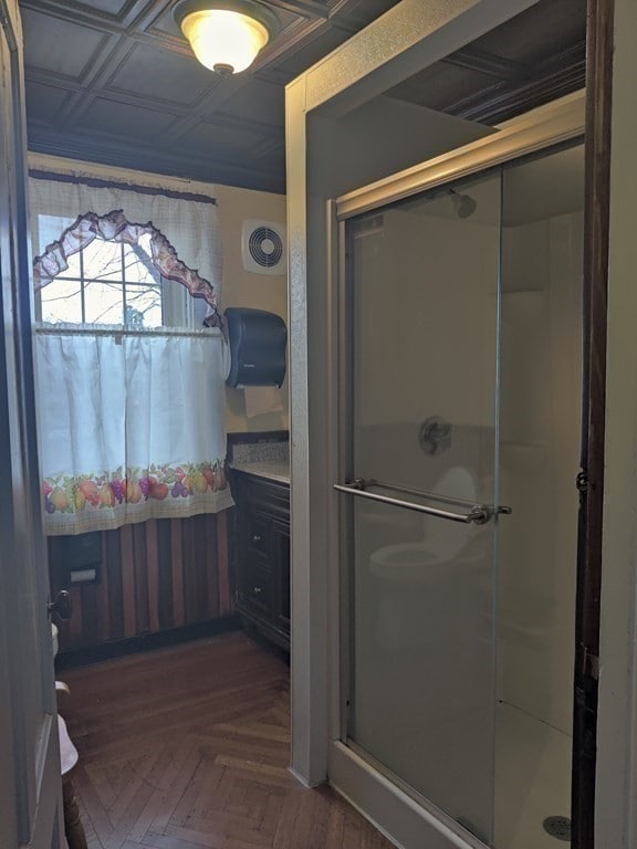 bathroom with parquet floors, vanity, and an enclosed shower