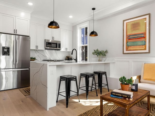 kitchen featuring a kitchen bar, kitchen peninsula, white cabinetry, and stainless steel appliances