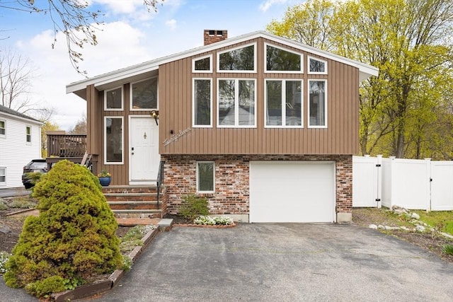 27 Johnson St, Malden, MA 02148 - view of front of property featuring asphalt driveway, a garage, a chimney, and brick siding