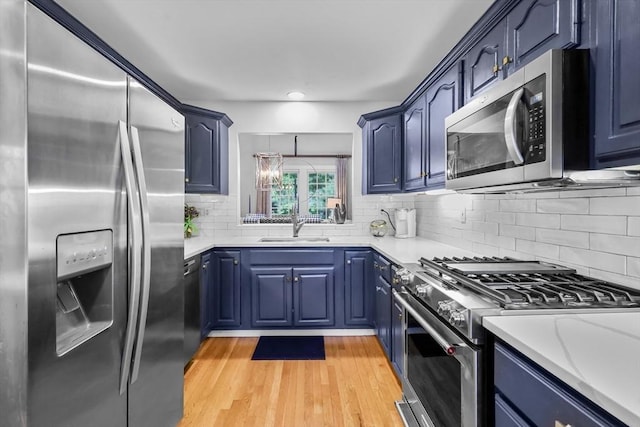 10 Highcroft Way Unit 10, Hopkinton, MA 01748 - kitchen featuring appliances with stainless steel finishes, blue cabinets, a sink, light countertops, and light wood-type flooring