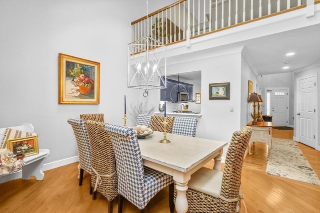 10 Highcroft Way Unit 10, Hopkinton, MA 01748 - dining space featuring light wood-style floors, baseboards, a high ceiling, a chandelier, and crown molding