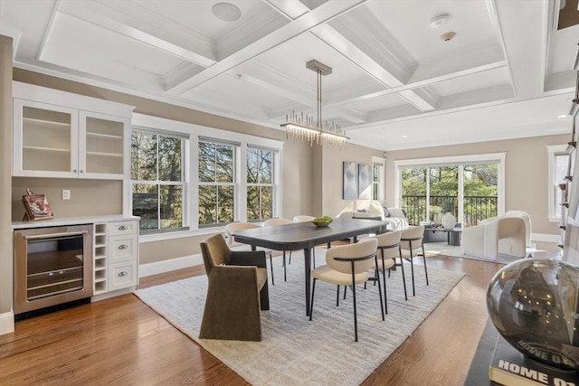 dining room featuring beverage cooler, coffered ceiling, light wood-type flooring, and baseboards