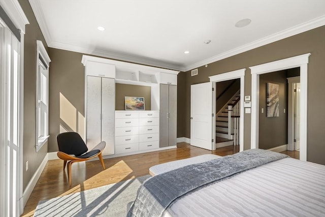 bedroom featuring visible vents, crown molding, baseboards, and wood finished floors