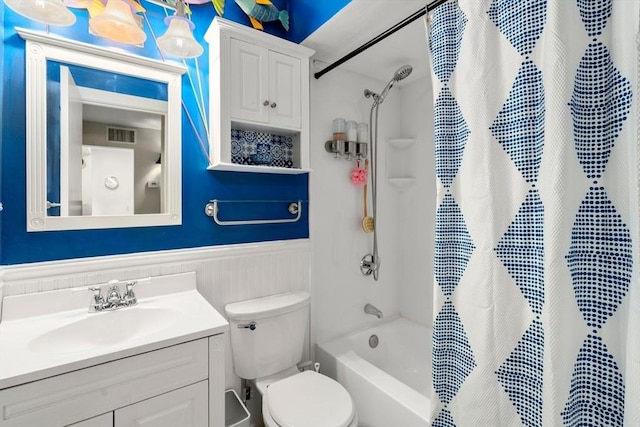 full bath with toilet, visible vents, vanity, wainscoting, and shower / bathtub combination with curtain