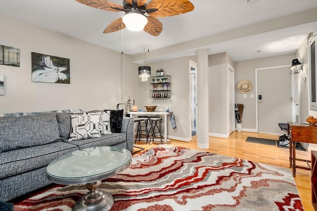 living room featuring wood finished floors, a ceiling fan, and baseboards