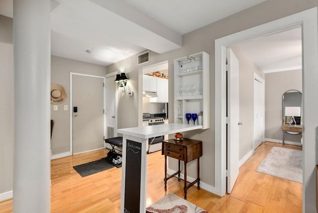 kitchen featuring visible vents, white cabinets, a kitchen breakfast bar, stainless steel electric stove, and light wood-style floors