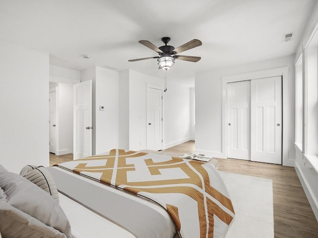 bedroom featuring ceiling fan, a closet, multiple windows, and light hardwood / wood-style flooring