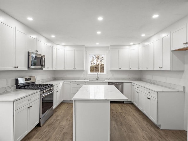 kitchen with hardwood / wood-style floors, sink, a kitchen island, white cabinetry, and stainless steel appliances