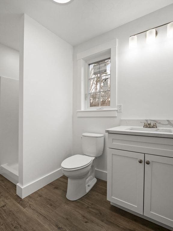 bathroom featuring hardwood / wood-style floors, vanity, toilet, and walk in shower