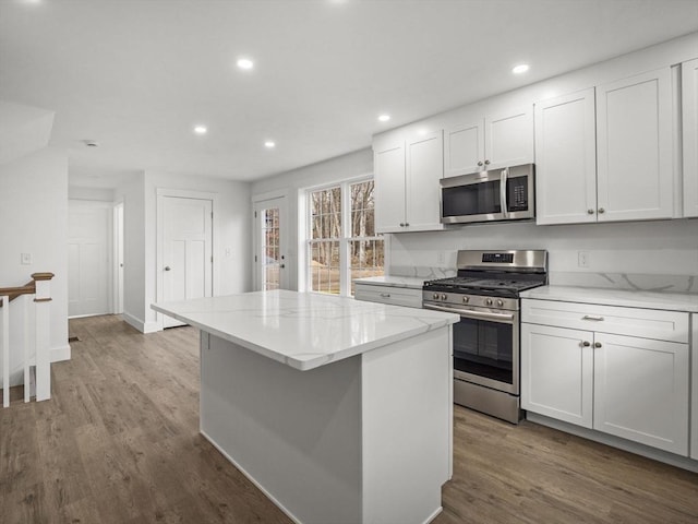 kitchen featuring appliances with stainless steel finishes, a center island, hardwood / wood-style flooring, and white cabinetry