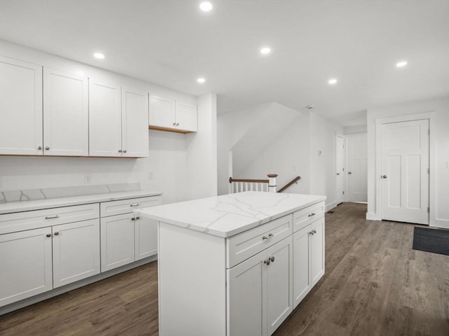 kitchen featuring light stone countertops, a center island, hardwood / wood-style flooring, and white cabinetry