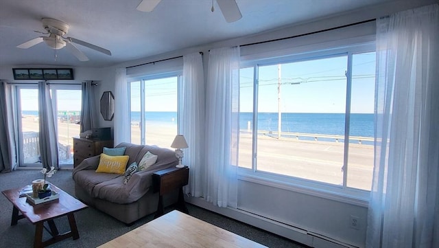 living room with a water view, ceiling fan, and a view of the beach