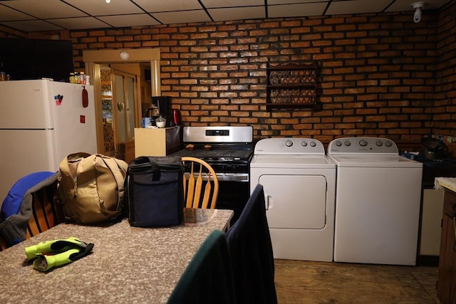 laundry room featuring brick wall and washer / clothes dryer