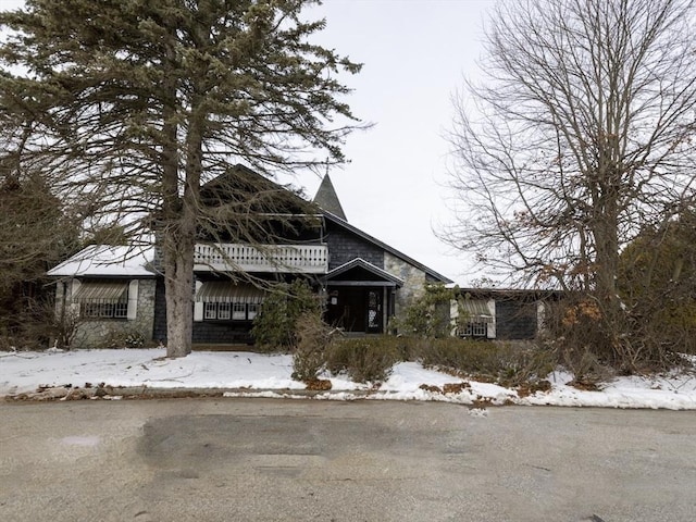 view of front of house featuring stone siding and a balcony