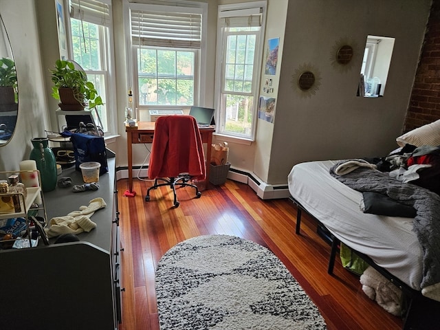 bedroom with wood-type flooring and a baseboard heating unit