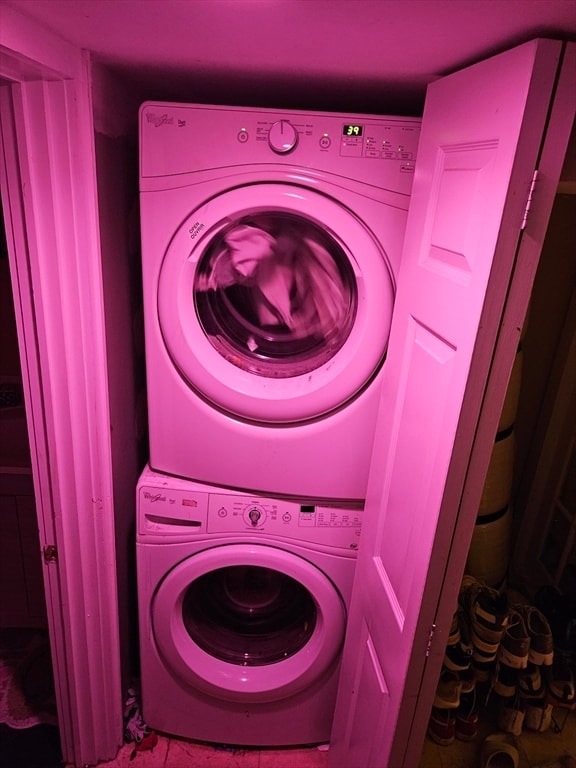 laundry area featuring tile patterned floors and stacked washer / dryer