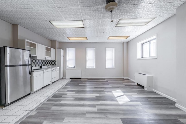 kitchen featuring backsplash, radiator, white cabinetry, and freestanding refrigerator